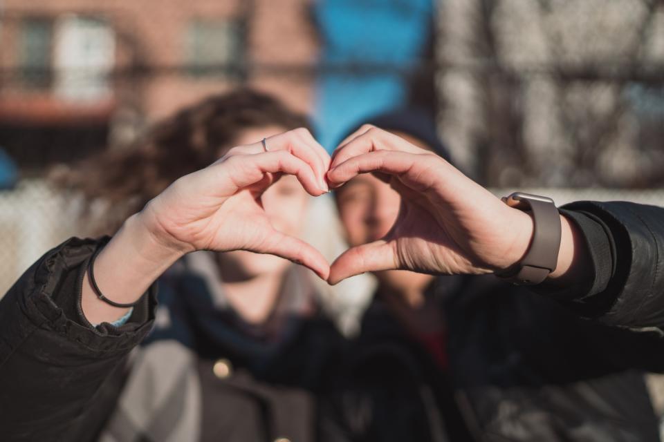 Two people with their hands in the shape of a heart.